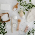 Elegant flat lay of organic bath essentials including soap, brush, and salts with greenery.